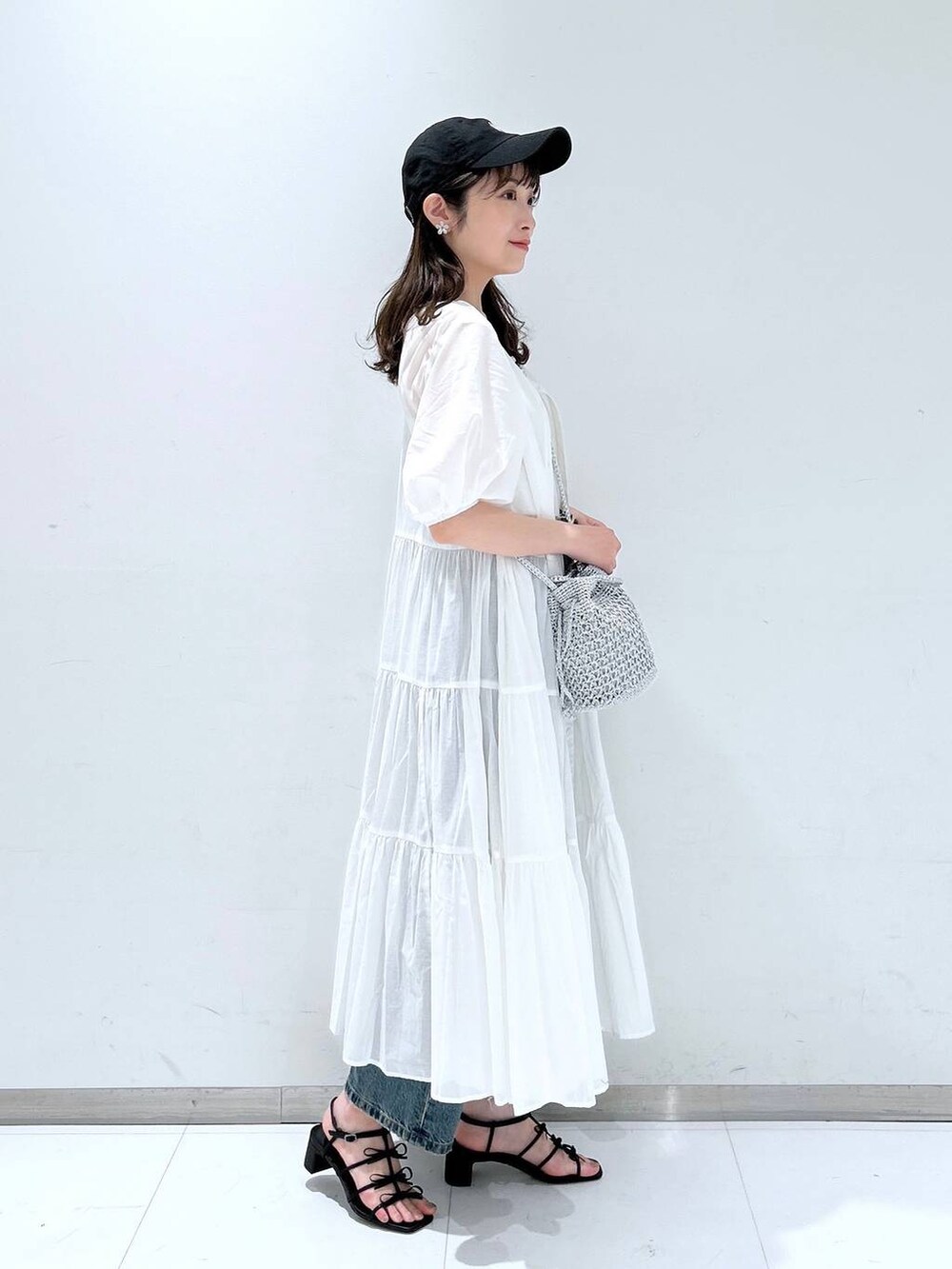ホワイト系のTシャツ/カットソー、ブラック系のサンダル、ブルー系のデニムパンツを着用したレディースの春コーディネートの4枚目の写真