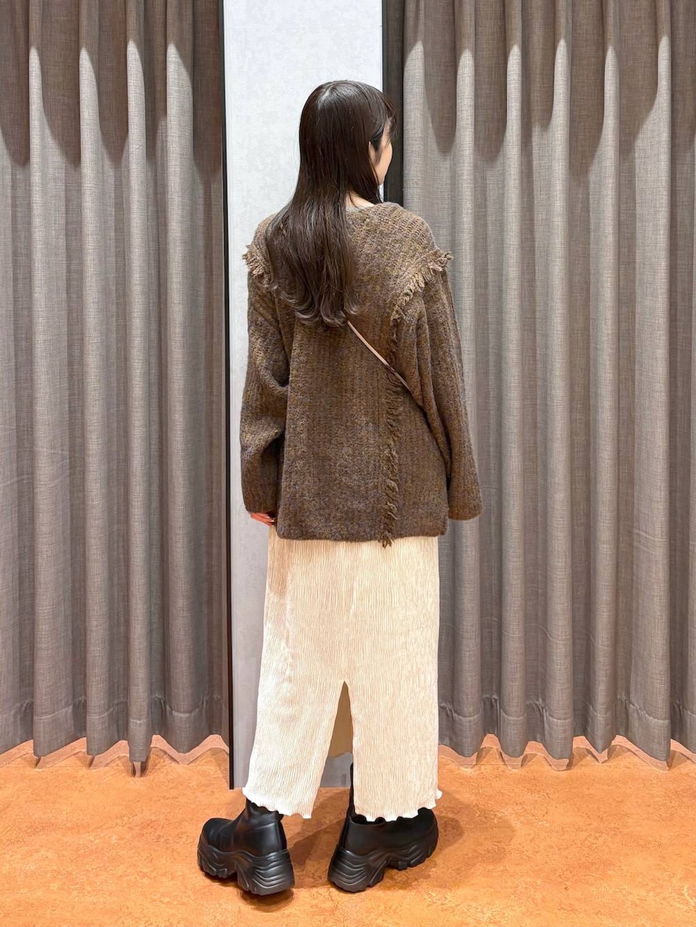 ブラウン系のニット/セーター、ホワイト系のTシャツ/カットソー、ブラック系のブーツを着用したレディースの冬コーディネートの4枚目の写真