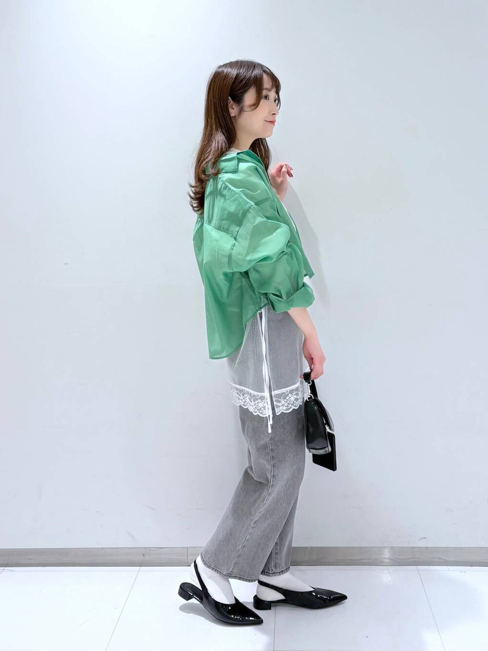 グリーン系のシャツ/ブラウス、グレー系のデニムパンツ、ブラック系のショルダーバッグを着用したレディースの春コーディネートの4枚目の写真