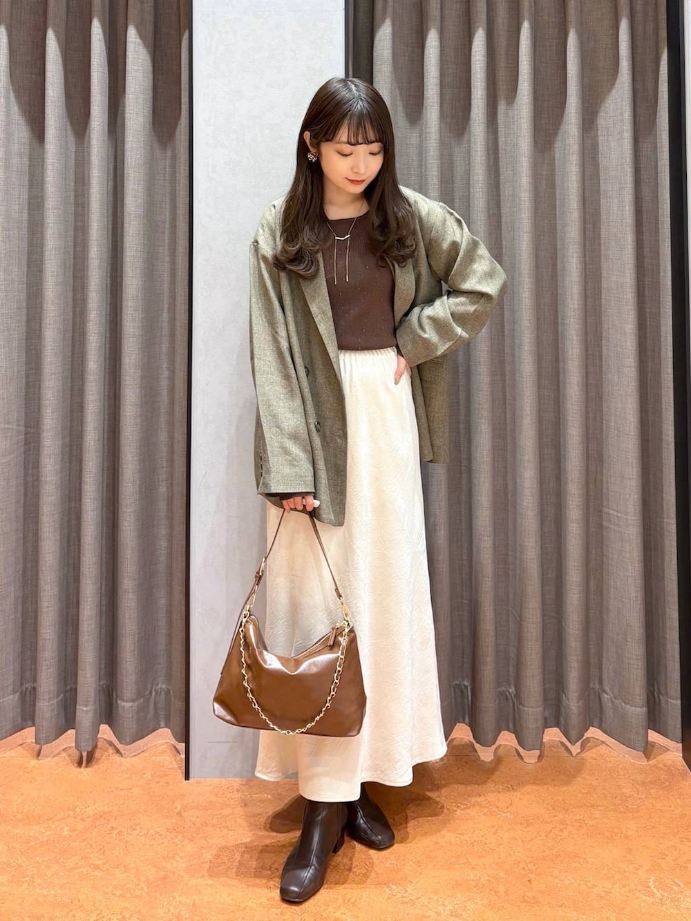 ホワイト系のスカート、ブラウン系のテーラードジャケット、ブラウン系のニット/セーターを着用したレディースの冬コーディネートの3枚目の写真