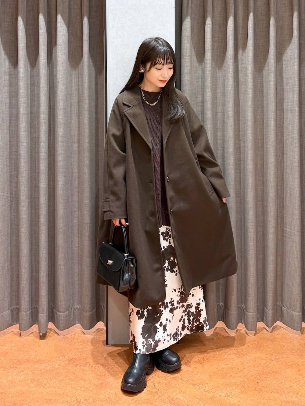 ブラック系のブーツ、その他のスカート、ブラウン系のニット/セーターを着用したレディースの冬コーディネートの2枚目の写真