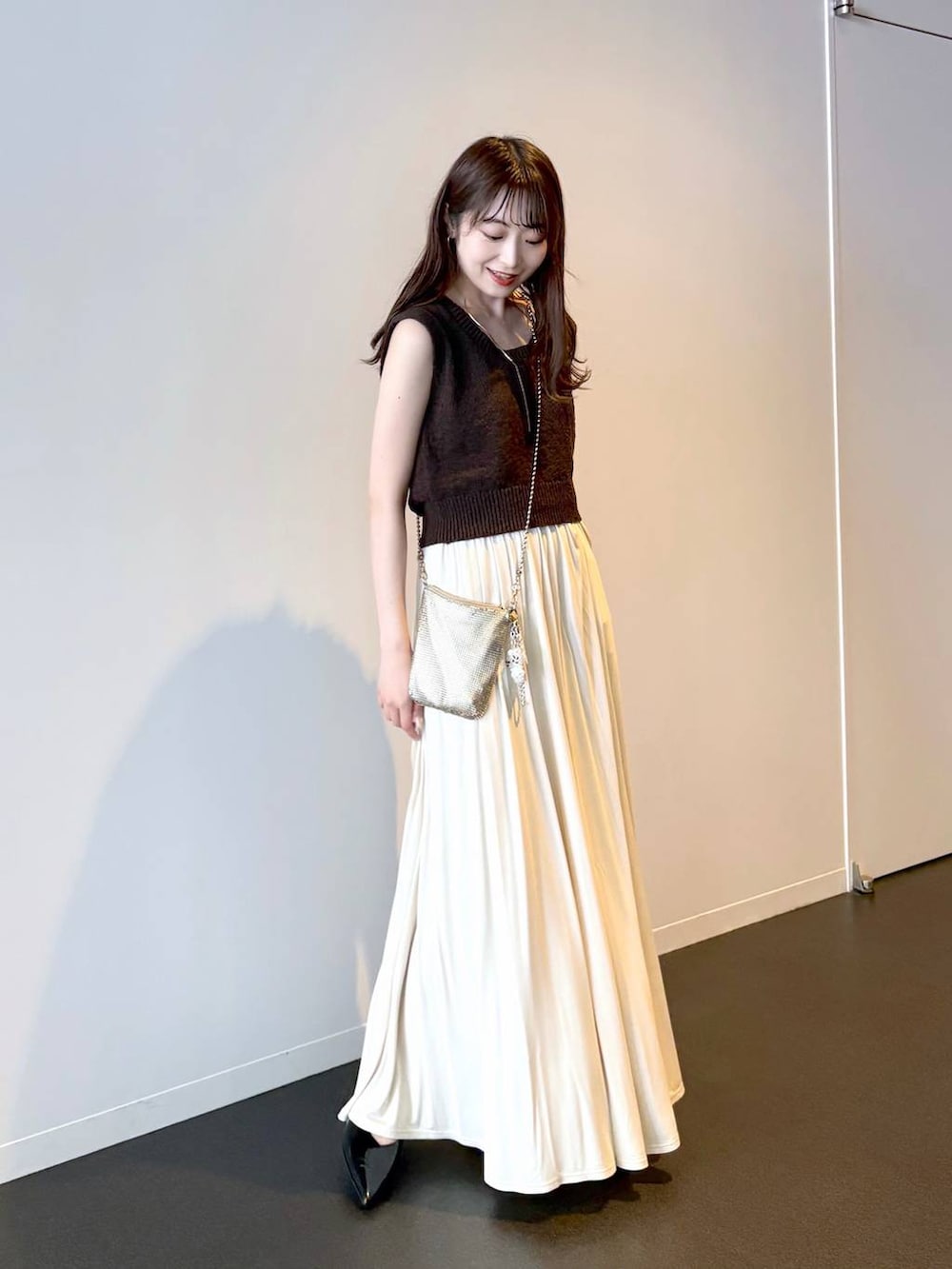 ゴールド系のショルダーバッグ、ブラック系のパンプス、ブラウン系のニット/セーターを着用したレディースの夏コーディネートの2枚目の写真