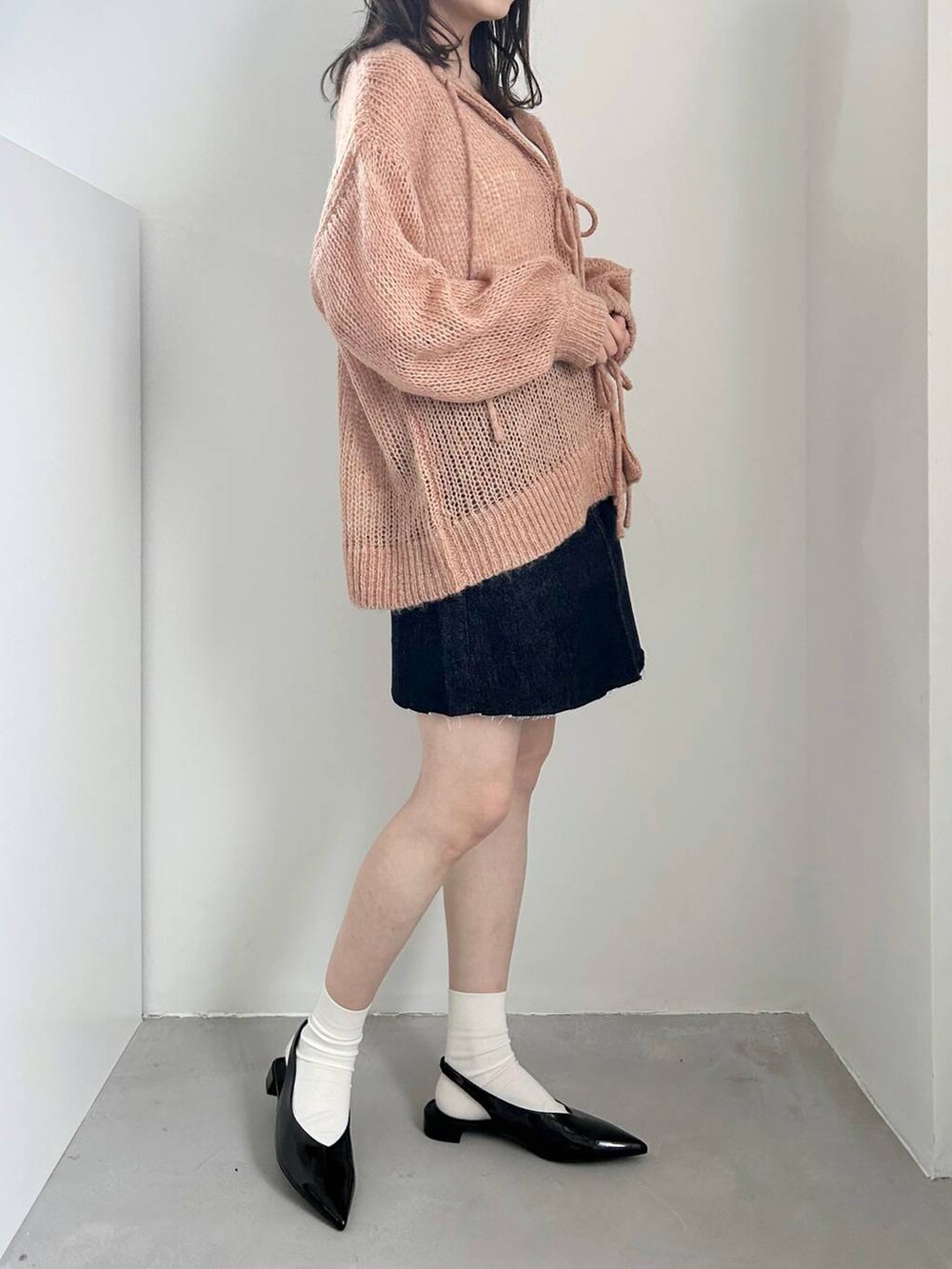 ブラック系のパンプス、ホワイト系のキャミソール、ブルー系のスカートを着用したレディースの冬コーディネートの3枚目の写真