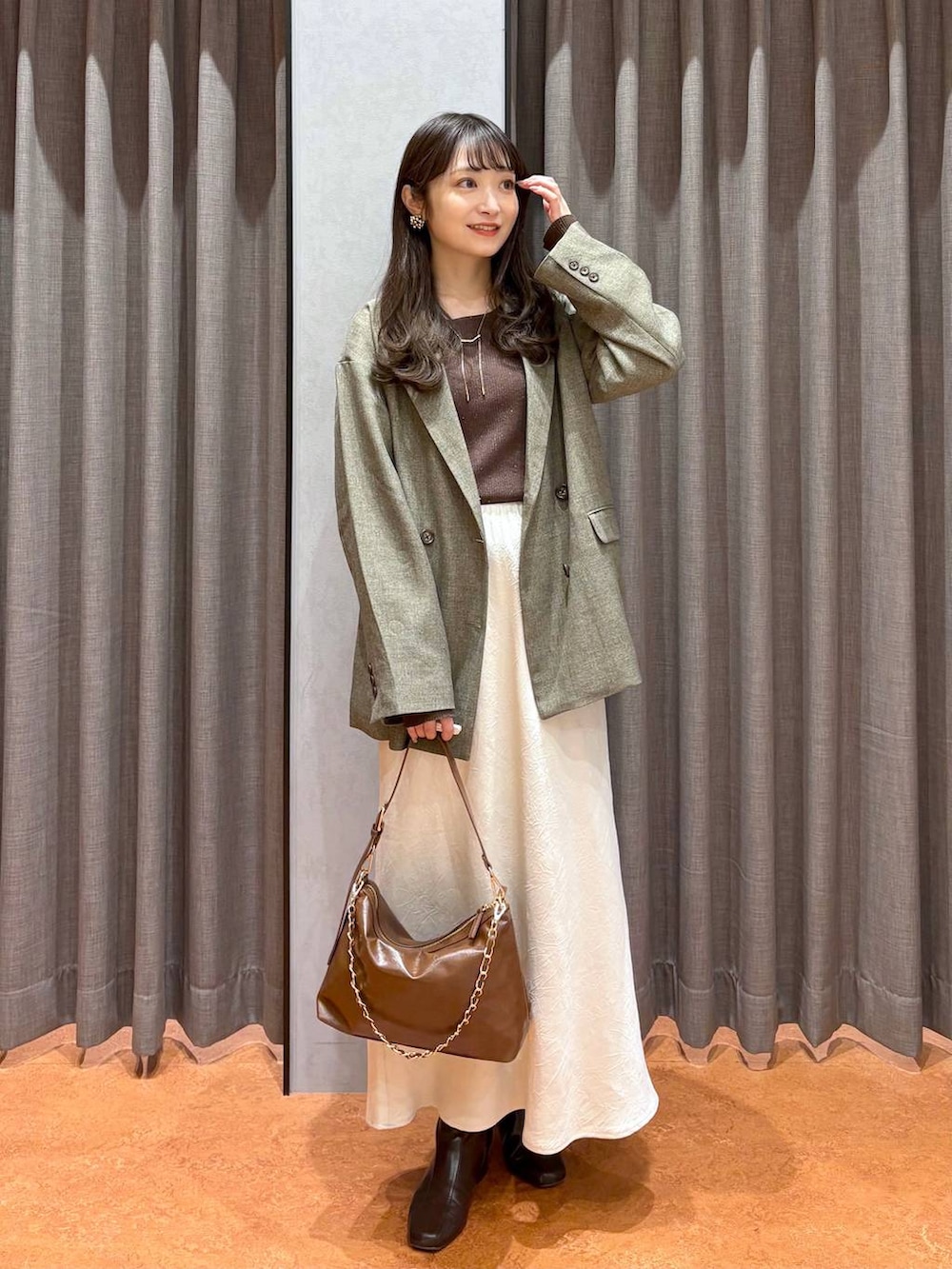 ホワイト系のスカート、ブラウン系のテーラードジャケット、ブラウン系のニット/セーターを着用したレディースの冬コーディネートの2枚目の写真