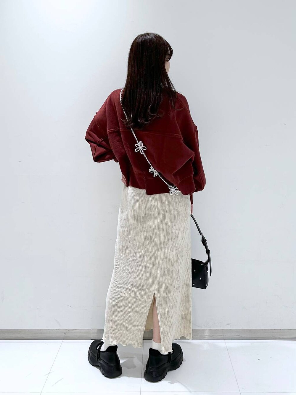 ブラック系のスニーカー、ホワイト系のスカート、ブラック系のショルダーバッグを着用したレディースの秋コーディネートの4枚目の写真