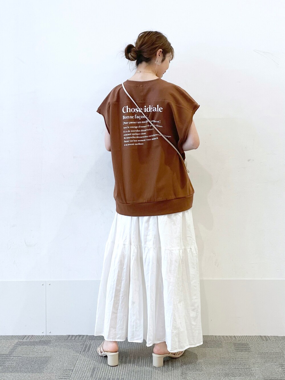 ホワイト系のスカート、ホワイト系のサンダル、ブラウン系のTシャツ/カットソーを着用したレディースの夏コーディネートの2枚目の写真