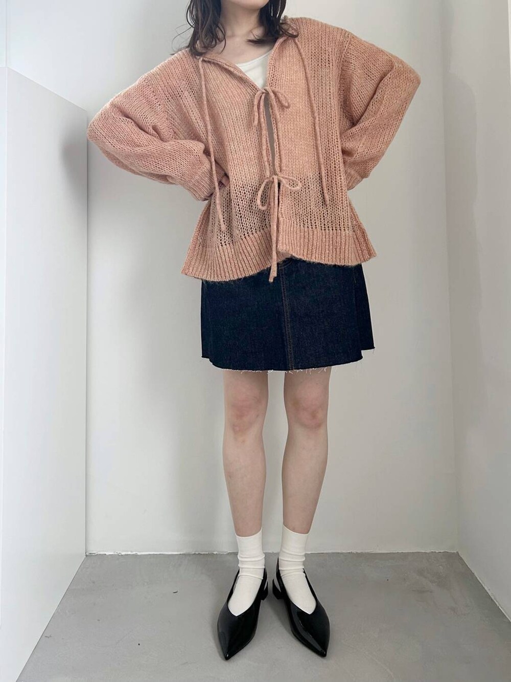 ブラック系のパンプス、ホワイト系のキャミソール、ブルー系のスカートを着用したレディースの冬コーディネートの2枚目の写真