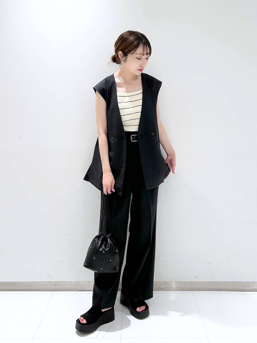 ブラック系のサンダル、ブラック系のショルダーバッグ、ホワイト系のタンクトップを着用したレディースの夏コーディネートの2枚目の写真