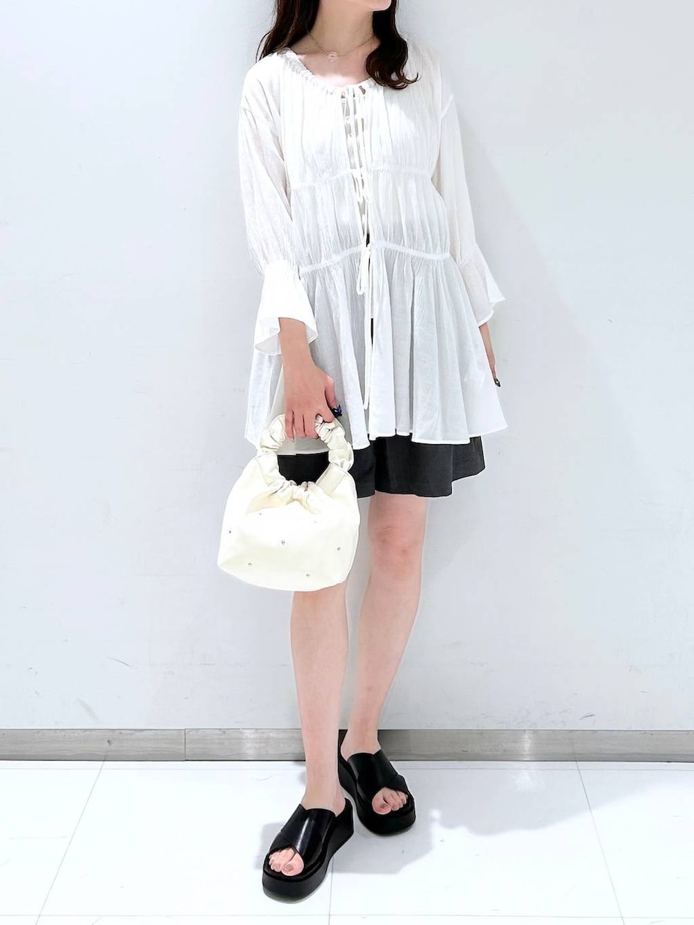 ベージュ系のハンドバッグ、ホワイト系のTシャツ/カットソー、ホワイト系のシャツ/ブラウスを着用したレディースの春コーディネートの4枚目の写真