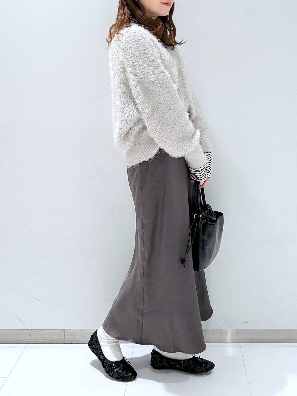グレー系のニット/セーター、ホワイト系のTシャツ/カットソー、グレー系のスカートを着用したレディースの冬コーディネートの2枚目の写真