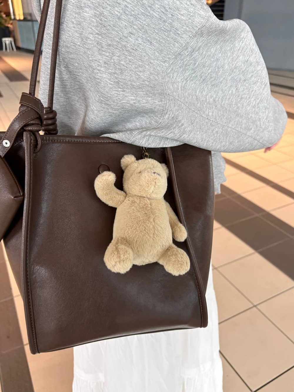 グレー系のパーカー、ブラウン系のトートバッグ、ホワイト系のパンプスを着用したレディースの春コーディネートの8枚目の写真