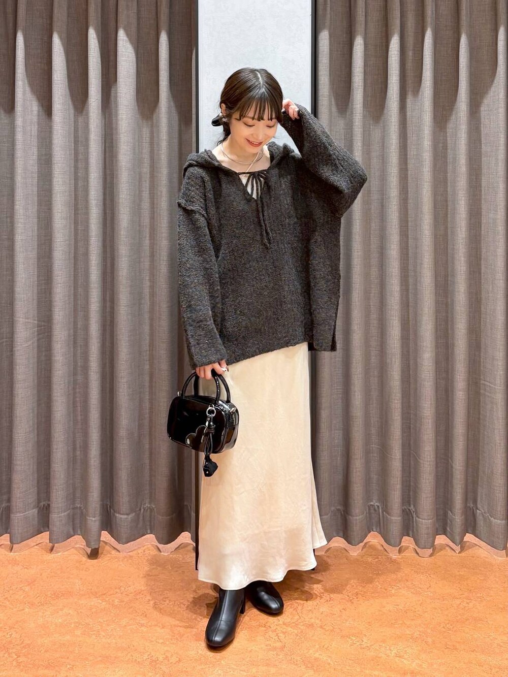 ベージュ系のキャミソール、ホワイト系のスカート、ブラック系のボストンバッグを着用したレディースの秋コーディネートの2枚目の写真