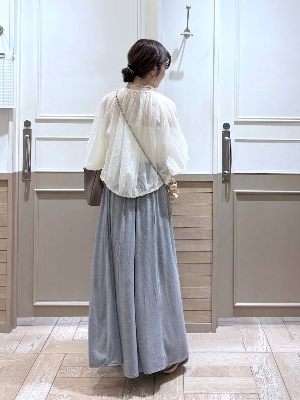 ゴールド系のショルダーバッグ、ホワイト系のサンダル、ホワイト系のブルゾンを着用したレディースの夏コーディネートの5枚目の写真