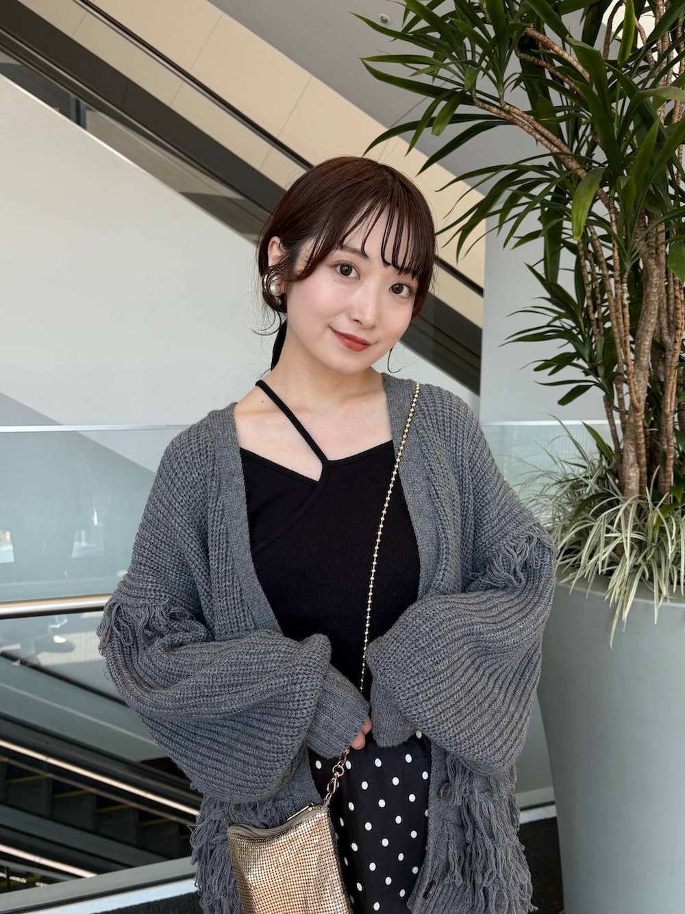 ゴールド系のショルダーバッグ、ブラック系のスカートを着用したレディースの春コーディネートの6枚目の写真