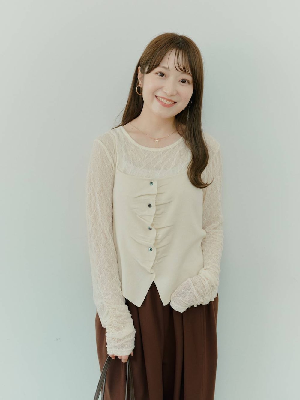 ブラウン系のボストンバッグ、ホワイト系のキャミソール、ホワイト系のTシャツ/カットソーを着用したレディースの秋コーディネートの2枚目の写真