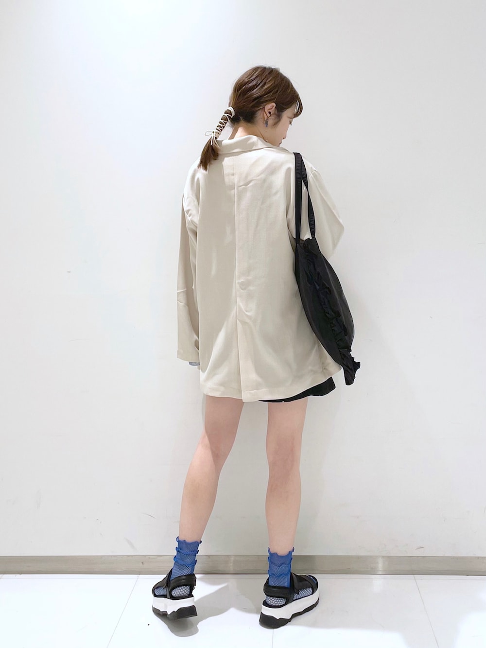 ブラック系のトートバッグ、ブルー系のシャツ/ブラウス、ホワイト系のテーラードジャケットを着用したレディースの春コーディネートの2枚目の写真