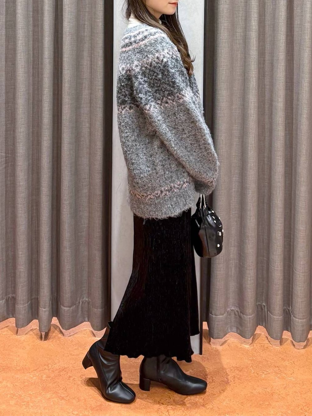 ホワイト系のニット/セーター、ブラック系のスカート、ブラック系のブーツを着用したレディースの冬コーディネートの3枚目の写真