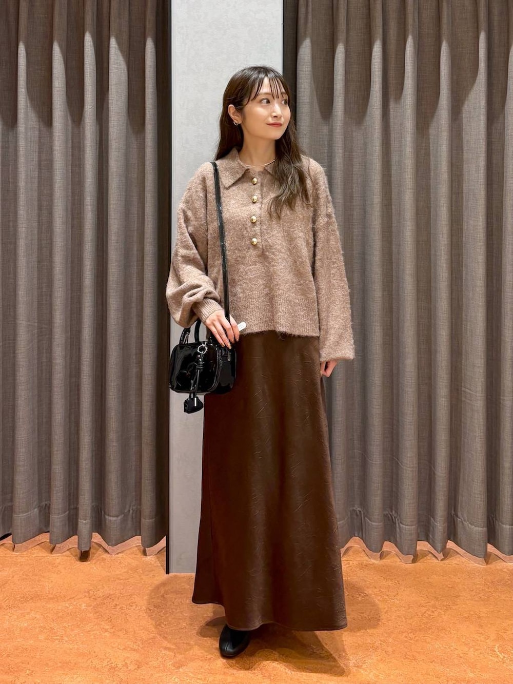 ブラウン系のスカート、ブラック系のボストンバッグ、ブラウン系のニット/セーターを着用したレディースの秋コーディネートの2枚目の写真