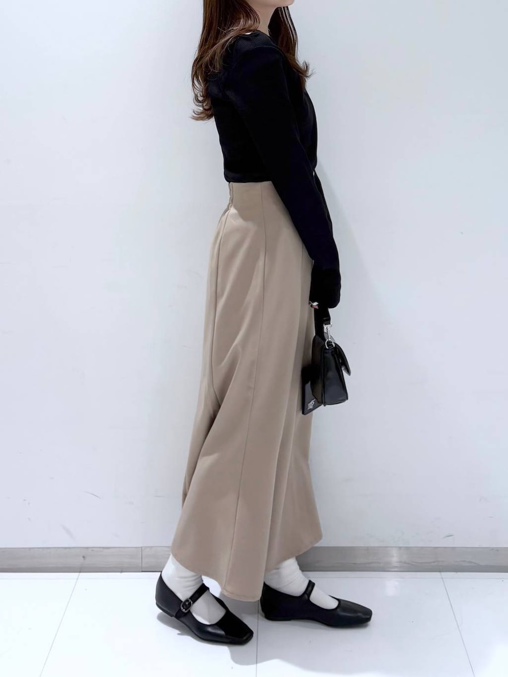 ブラック系のバレエシューズ、ブラック系のショルダーバッグ、ベージュ系のスカートを着用したレディースの冬コーディネートの4枚目の写真