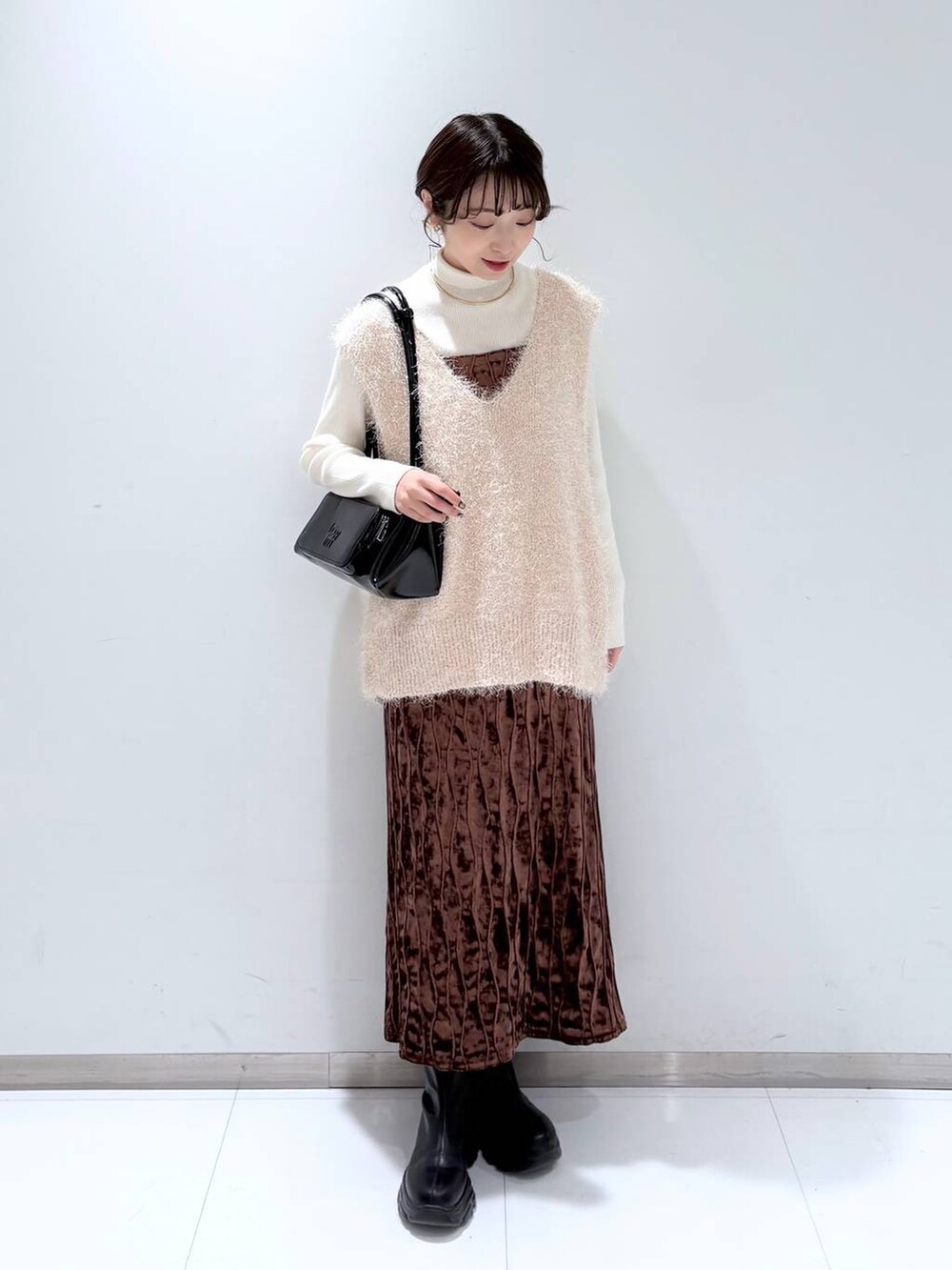 ホワイト系のニット/セーター、ブラック系のショルダーバッグ、ブラック系のブーツを着用したレディースの冬コーディネートの2枚目の写真