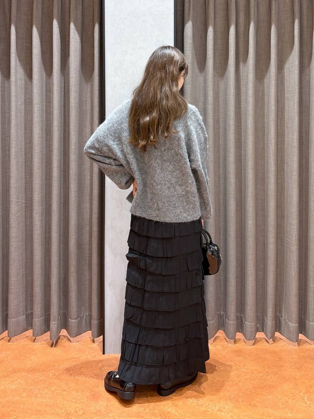 ブラック系のスカート、ブラック系のローファー、ブラック系のボストンバッグを着用したレディースの秋コーディネートの4枚目の写真