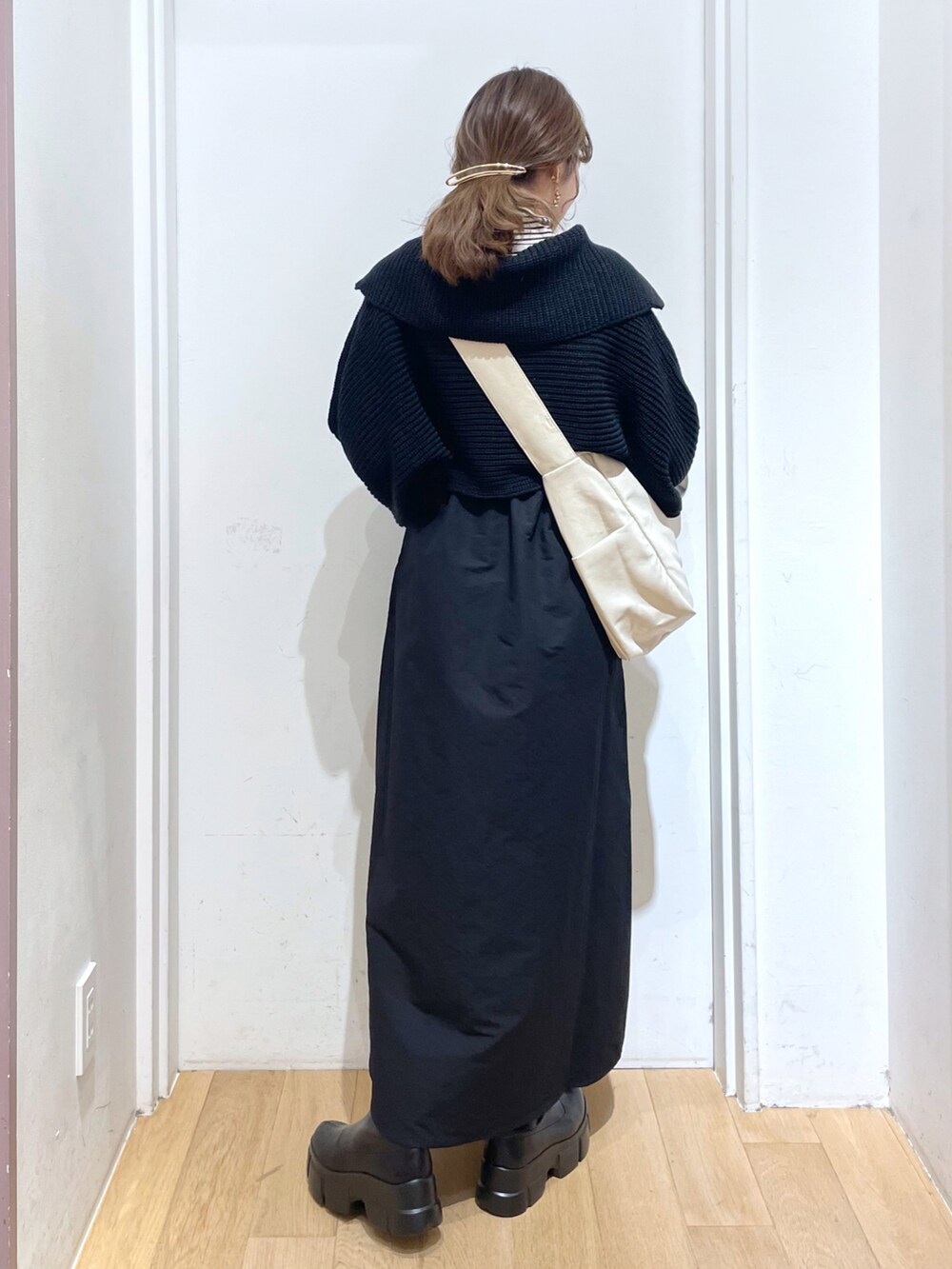 ブラック系のブーツ、ブラック系のワンピース、ホワイト系のボディバッグ/ウエストポーチを着用したレディースの冬コーディネートの2枚目の写真