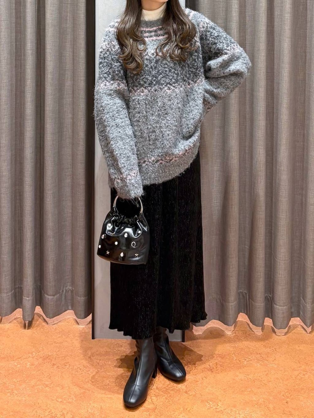 ホワイト系のニット/セーター、ブラック系のスカート、ブラック系のブーツを着用したレディースの冬コーディネートの2枚目の写真