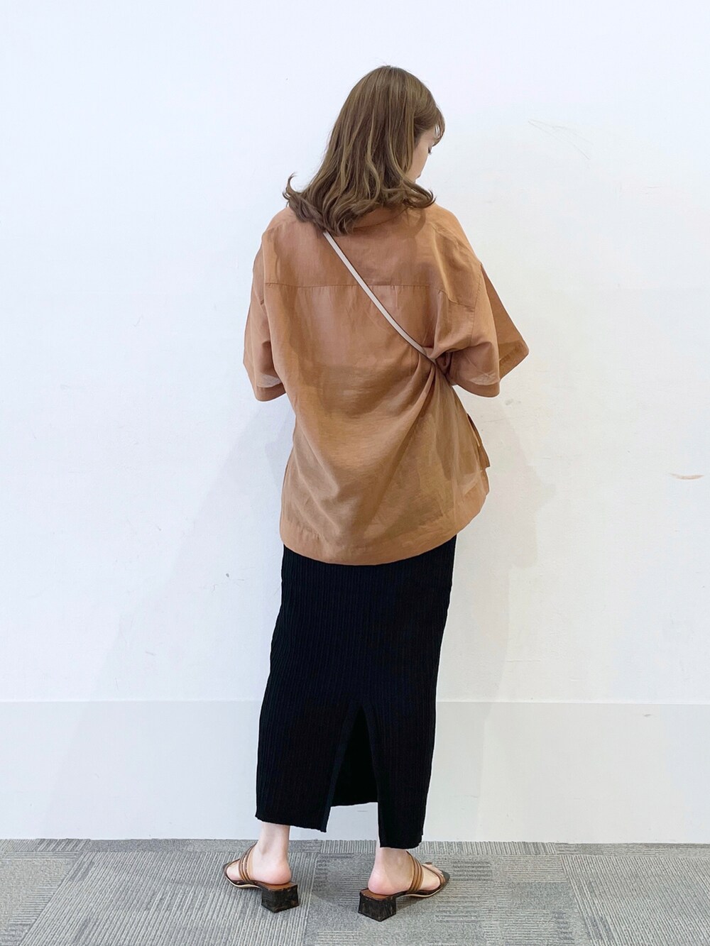 ブラウン系のサンダル、ブラック系のスカート、ホワイト系のショルダーバッグを着用したレディースの夏コーディネートの2枚目の写真