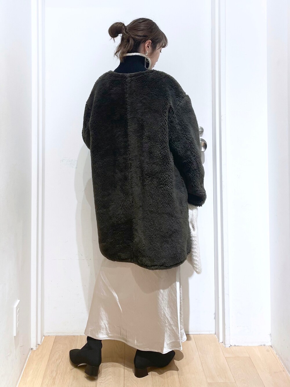 ブラック系のニット/セーター、グリーン系のミリタリージャケット、ホワイト系のトートバッグを着用したレディースの冬コーディネートの2枚目の写真