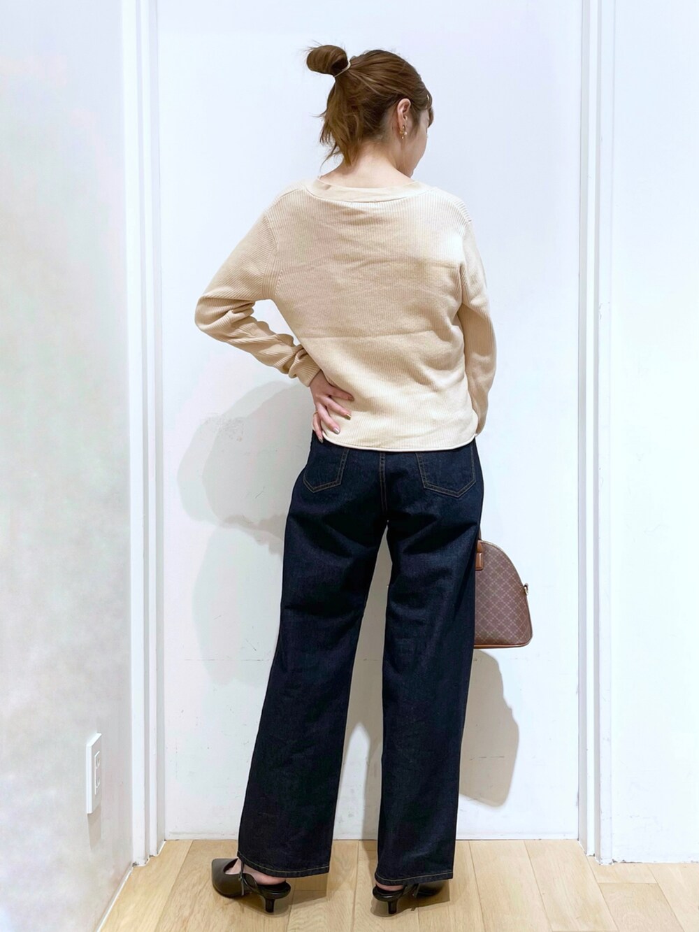 ブルー系のデニムパンツ、ブラック系のサンダル、ブラウン系のボストンバッグを着用したレディースの夏コーディネートの2枚目の写真