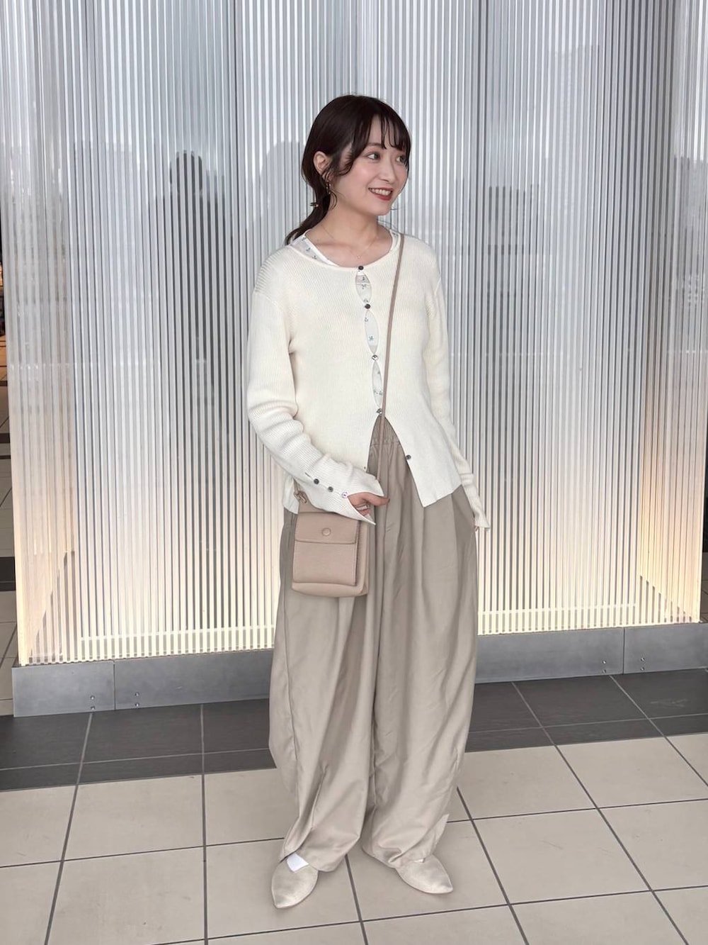 ホワイト系のニット/セーター、ベージュ系のその他パンツ、ホワイト系のTシャツ/カットソーを着用したレディースの春コーディネートの2枚目の写真