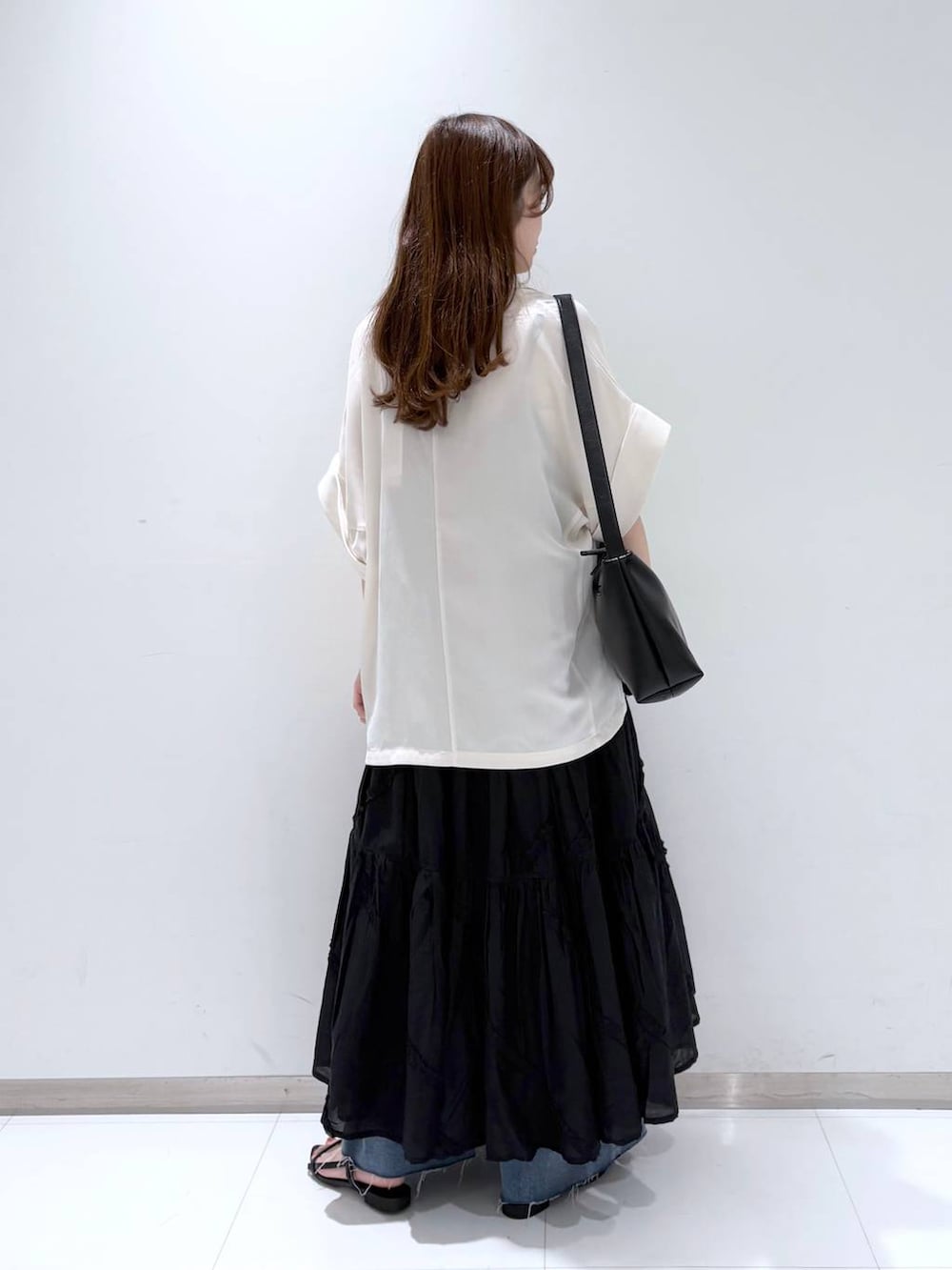 ホワイト系のTシャツ/カットソー、ブラック系のサンダル、ブルー系のデニムパンツを着用したレディースの春コーディネートの4枚目の写真