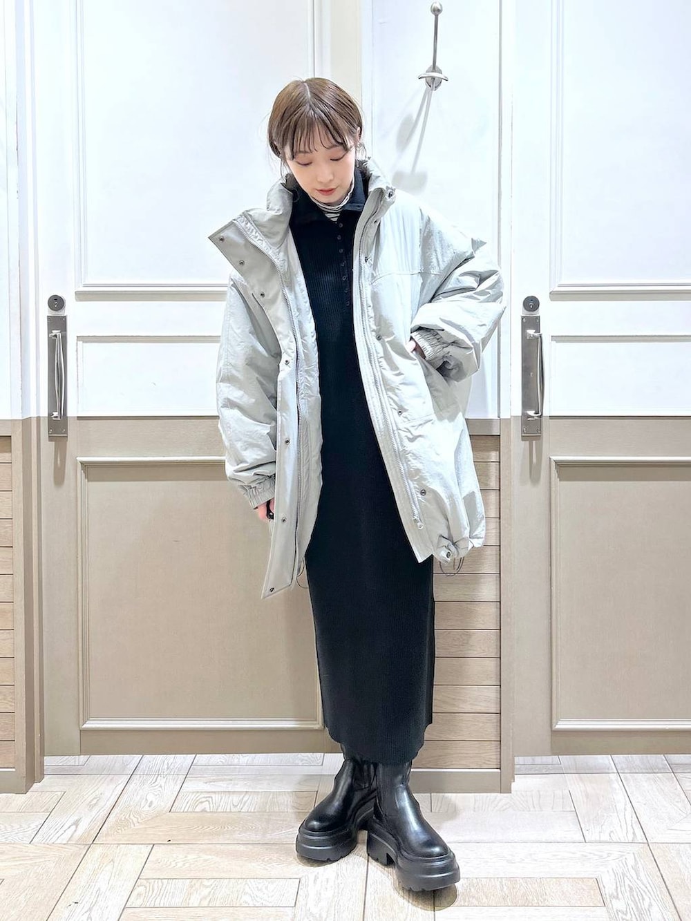 ホワイト系のTシャツ/カットソー、グリーン系のダウンジャケット/コート、ブラック系のブーツを着用したレディースの冬コーディネートの2枚目の写真