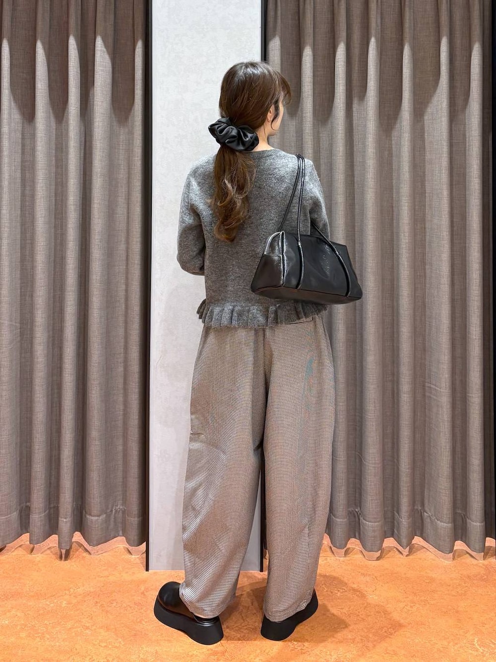 ブラック系のサンダル、ブラック系のボストンバッグ、グレー系のニット/セーターを着用したレディースの秋コーディネートの4枚目の写真