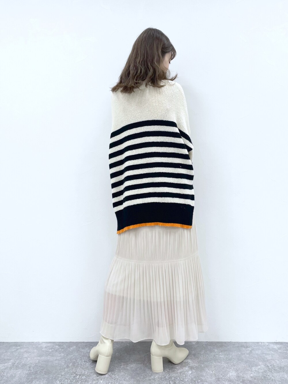 ホワイト系のスカート、ホワイト系のブーツ、ホワイト系のニット/セーターを着用したレディースの冬コーディネートの2枚目の写真