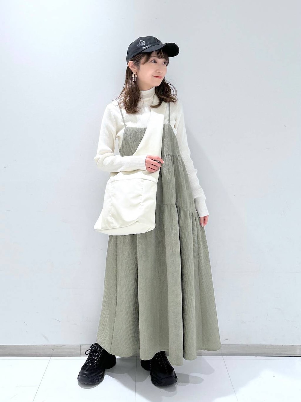 グリーン系のワンピース、ホワイト系のニット/セーター、ブラック系のスニーカーを着用したレディースの冬コーディネートの3枚目の写真