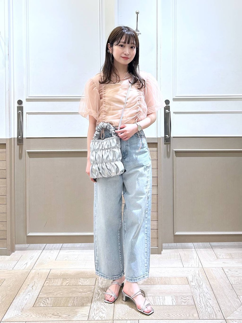 シルバー系のサンダル、ベージュ系のTシャツ/カットソー、ブルー系のデニムパンツを着用したレディースの春コーディネートの2枚目の写真