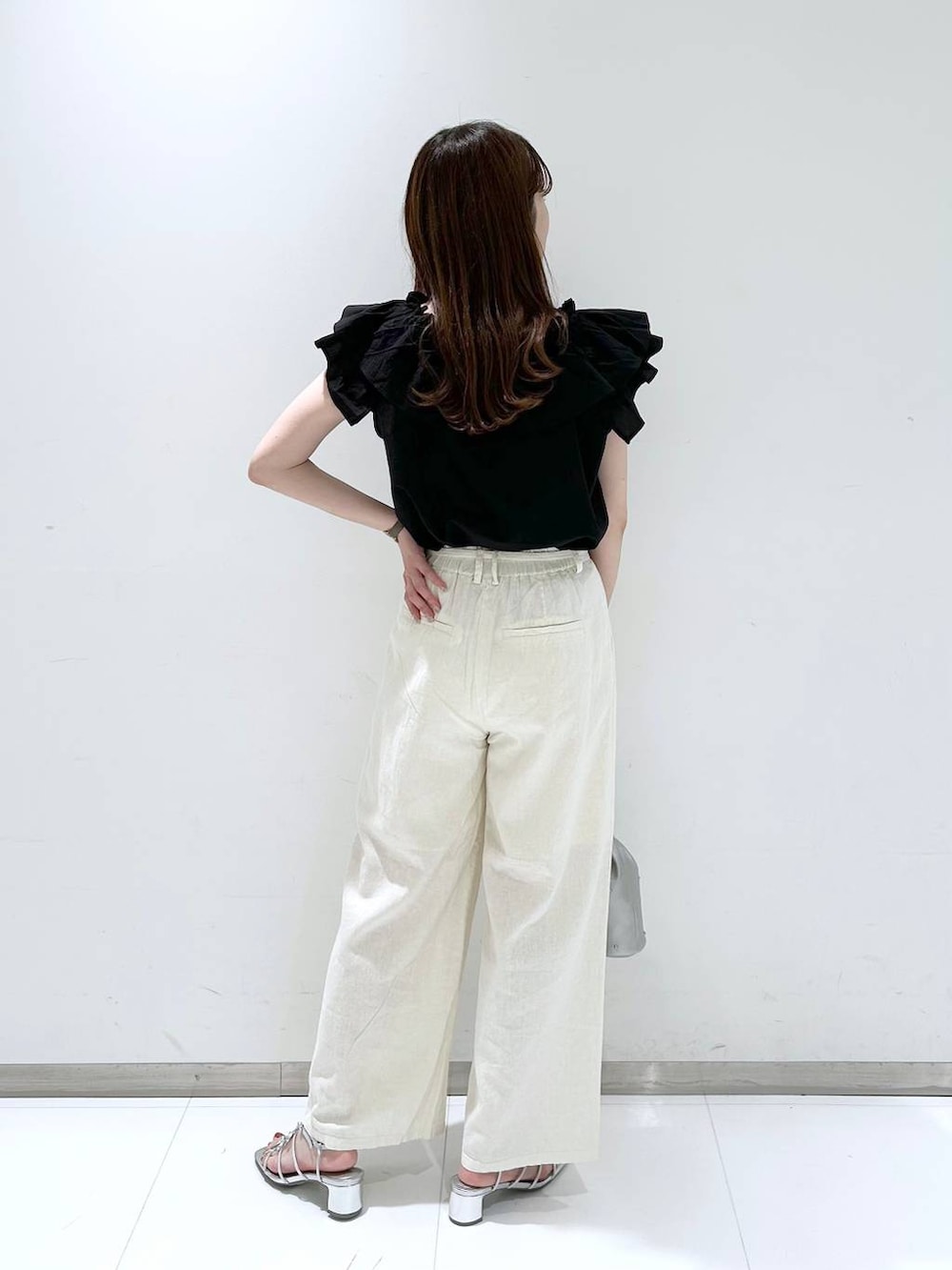 シルバー系のショルダーバッグ、シルバー系のサンダル、ホワイト系のスラックスを着用したレディースの夏コーディネートの4枚目の写真