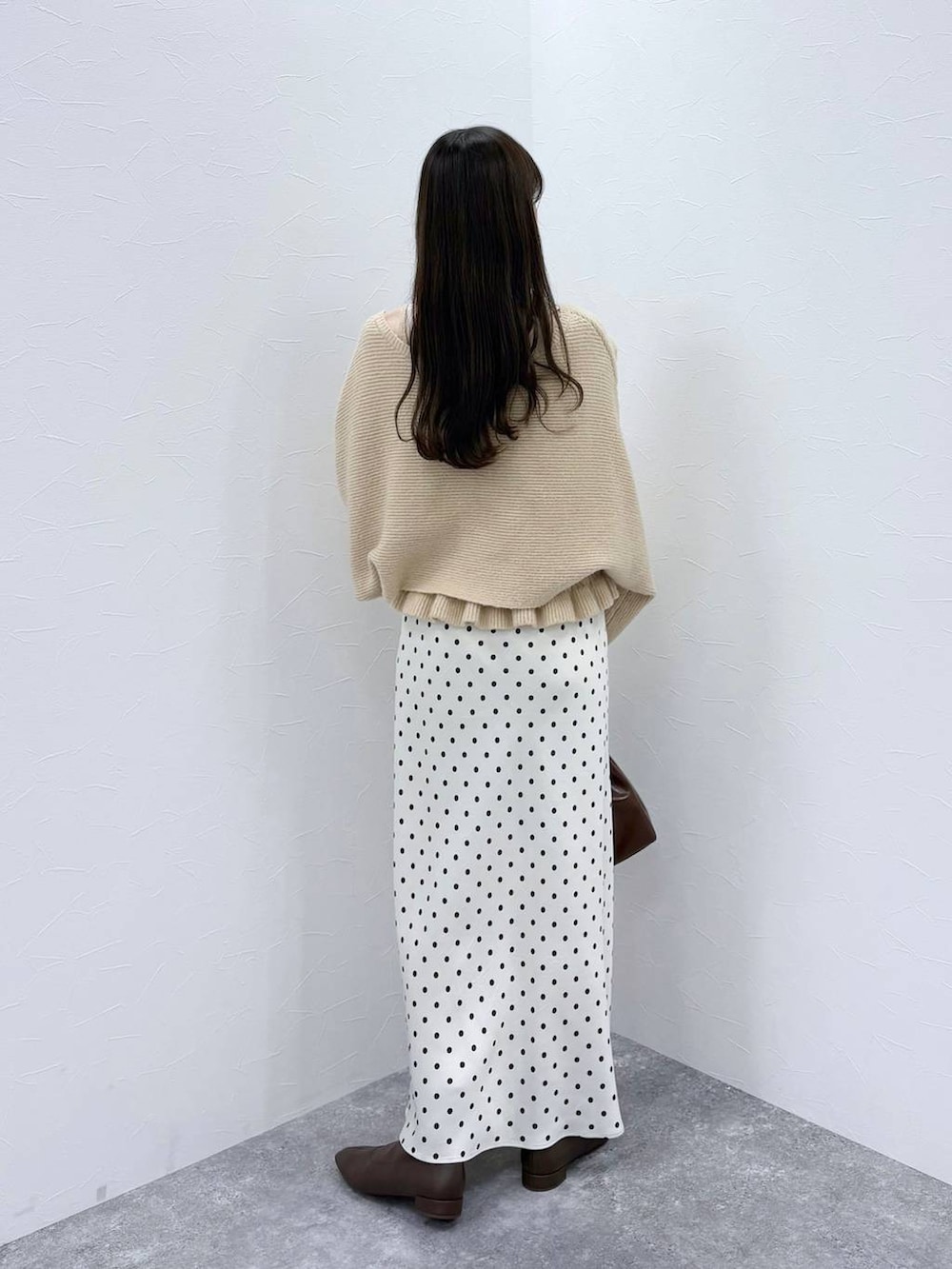 ホワイト系のスカート、ベージュ系のニット/セーター、ブラウン系のブーツを着用したレディースの秋コーディネートの4枚目の写真