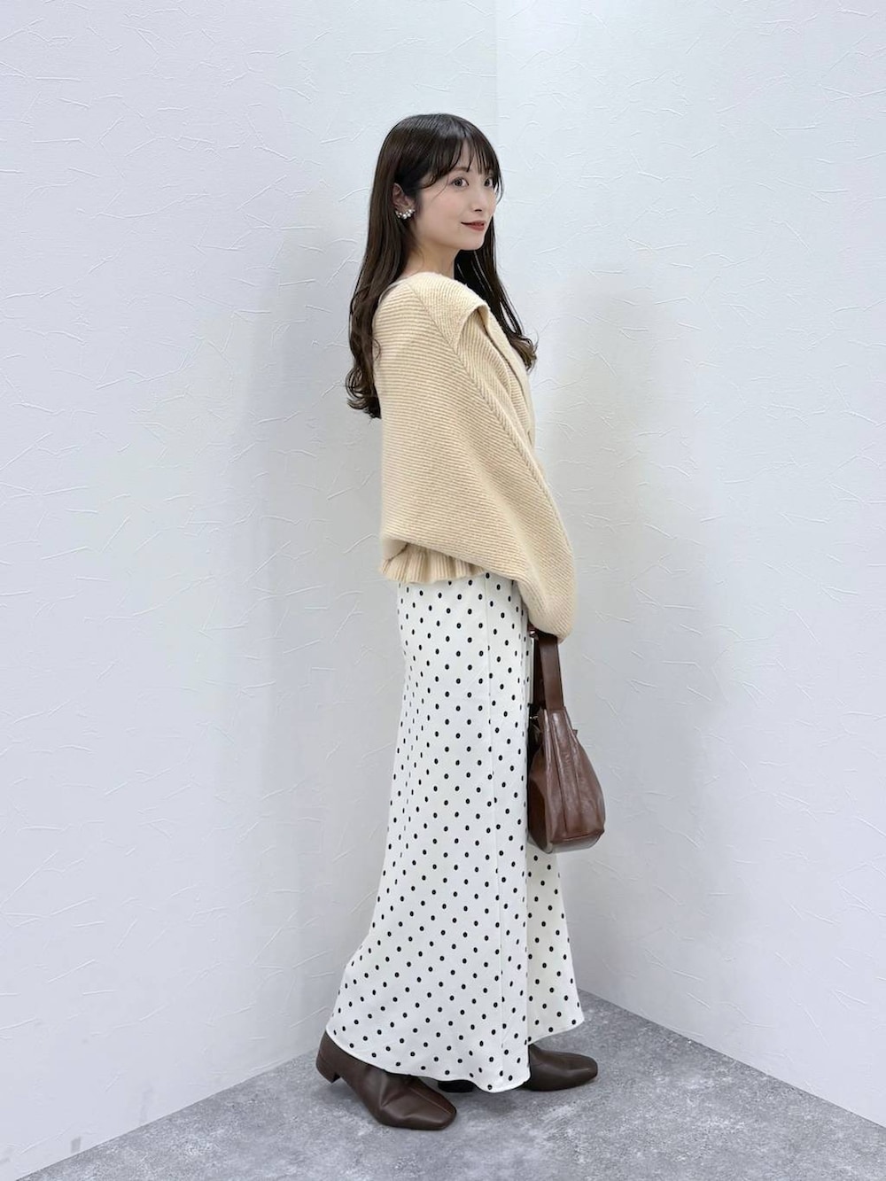 ホワイト系のスカート、ベージュ系のニット/セーター、ブラウン系のブーツを着用したレディースの秋コーディネートの3枚目の写真