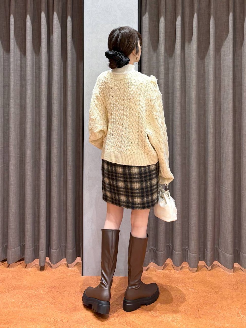 ブラウン系のステンカラーコート、ホワイト系のニット/セーター、ブラウン系のブーツを着用したレディースの冬コーディネートの8枚目の写真