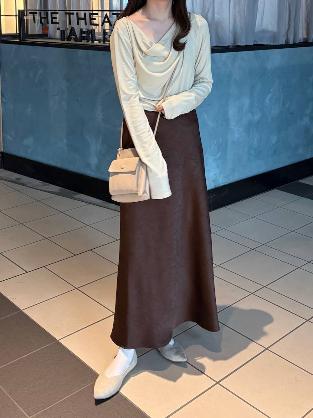 ブラウン系のスカート、ホワイト系のパンプス、ベージュ系のTシャツ/カットソーを着用したレディースの冬コーディネートの6枚目の写真