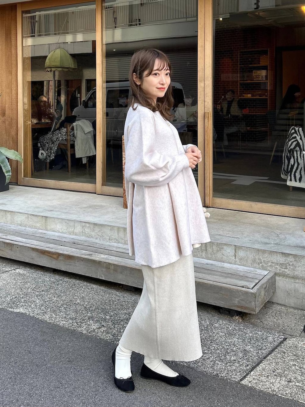 ホワイト系のニット/セーター、グレー系のスカート、ゴールド系のイヤリングを着用したレディースの冬コーディネートの2枚目の写真