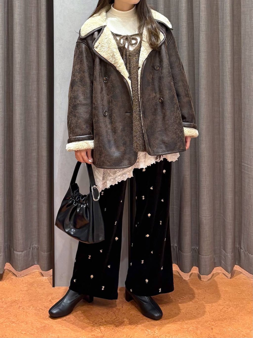 ブラウン系のニット/セーター、ホワイト系のニット/セーター、ブラウン系のムートンコートを着用したレディースの冬コーディネートの2枚目の写真