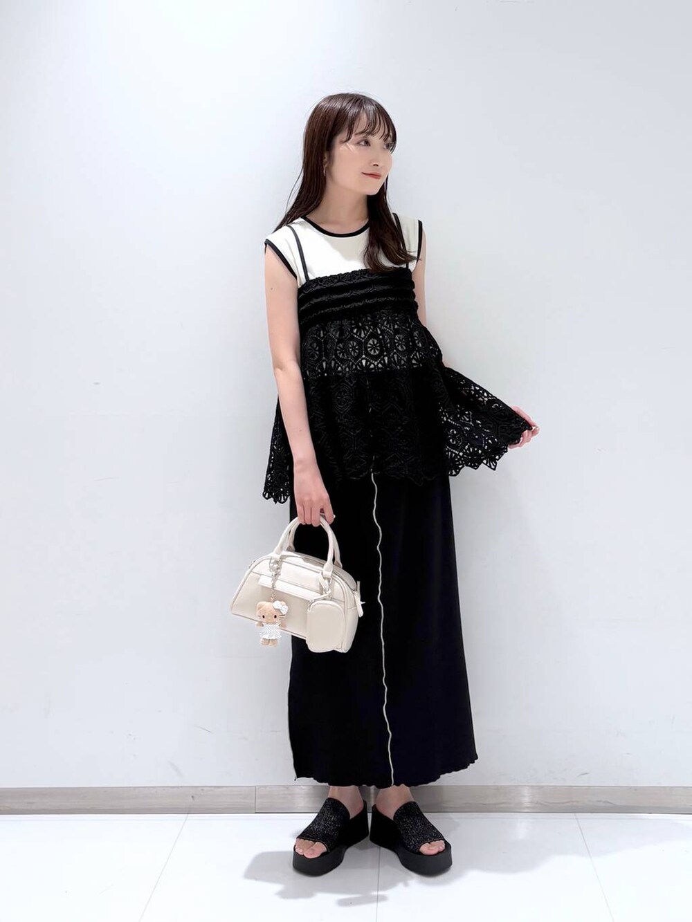 ブラック系のサンダル、ブラック系のキャミソール、ホワイト系のショルダーバッグを着用したレディースの夏コーディネートの2枚目の写真