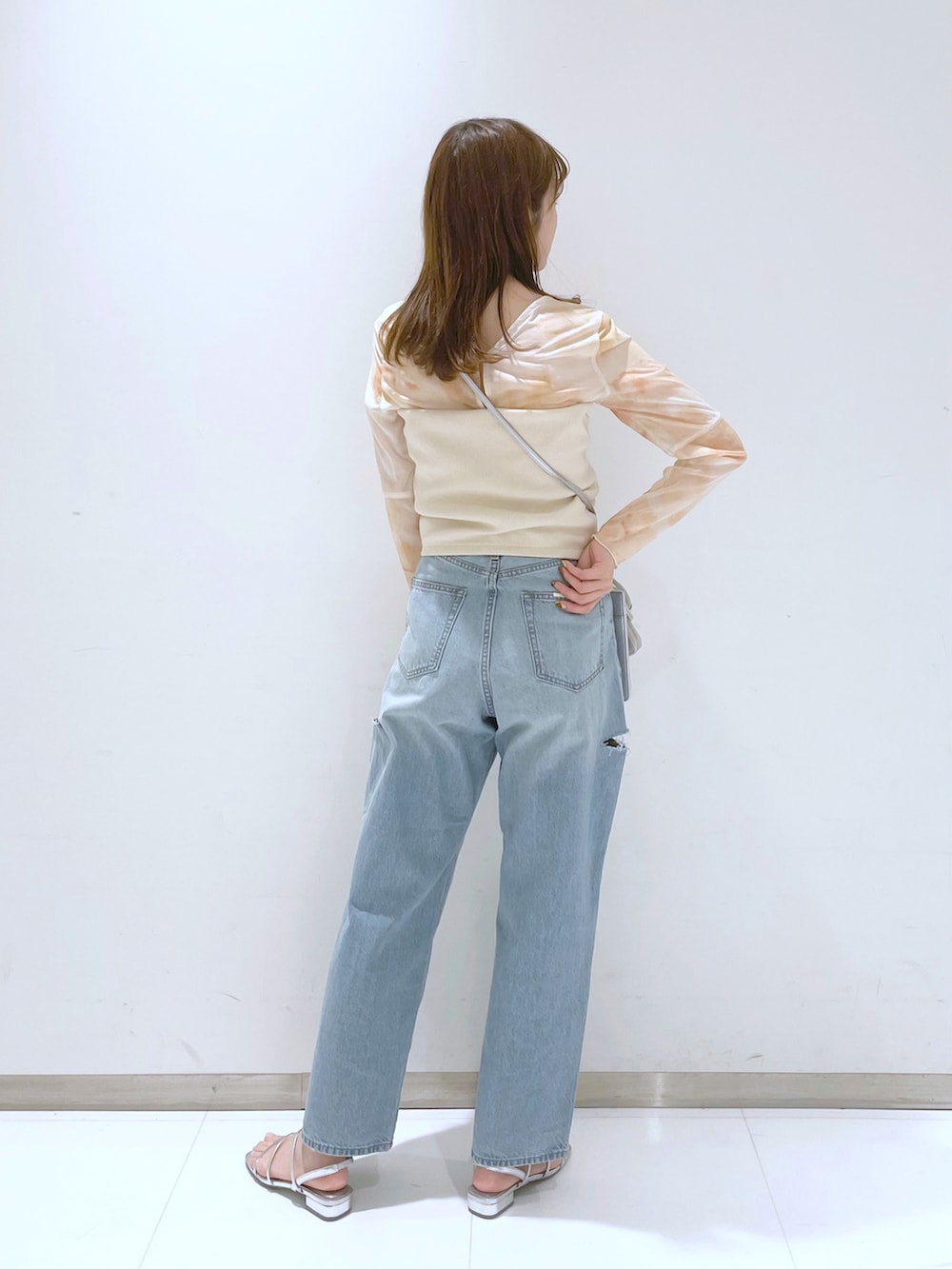ブルー系のデニムパンツ、シルバー系のサンダル、シルバー系のショルダーバッグを着用したレディースの夏コーディネートの2枚目の写真