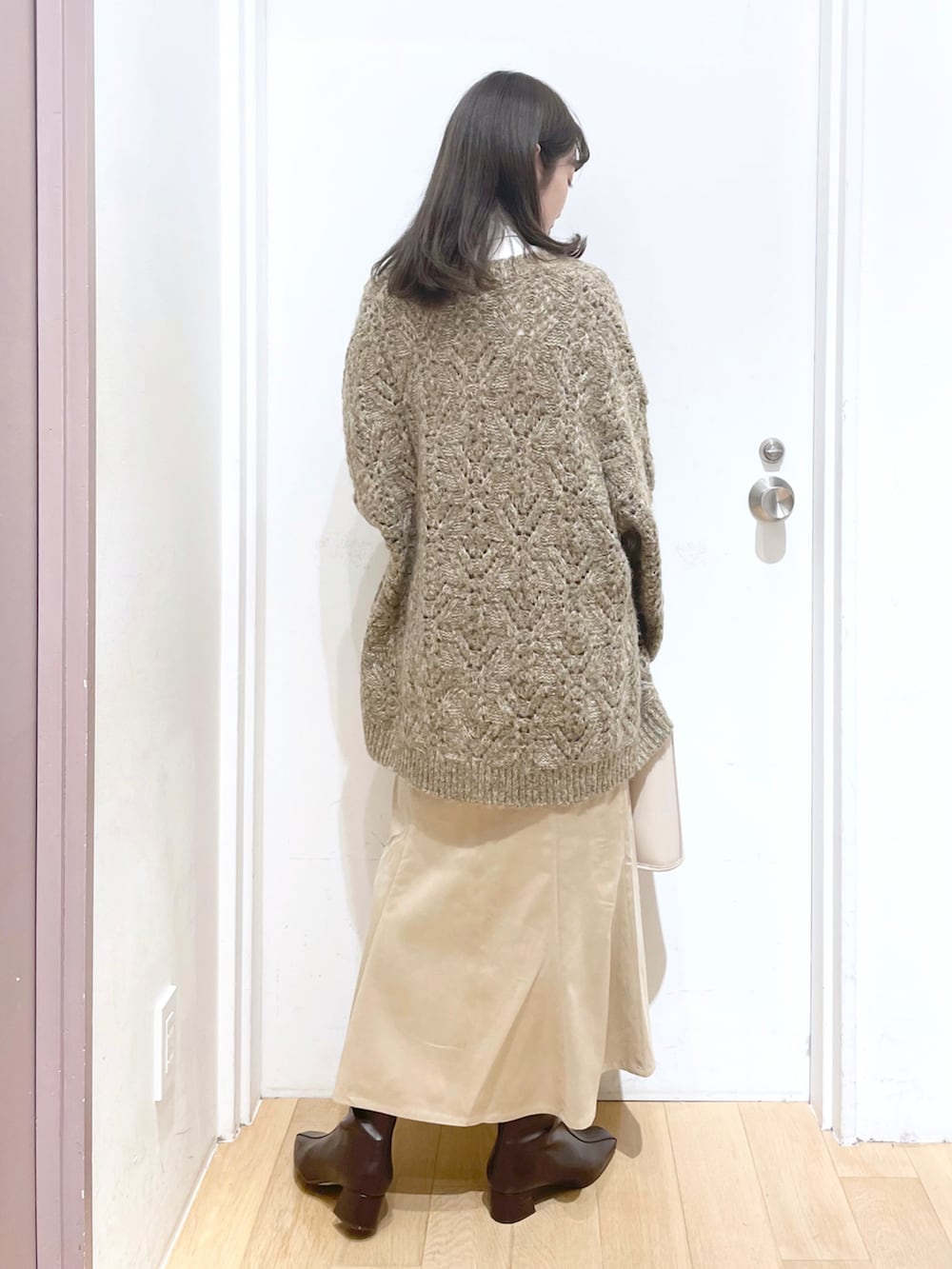 ホワイト系のスカート、ホワイト系のショルダーバッグ、ブラウン系のブーツを着用したレディースの秋コーディネートの2枚目の写真