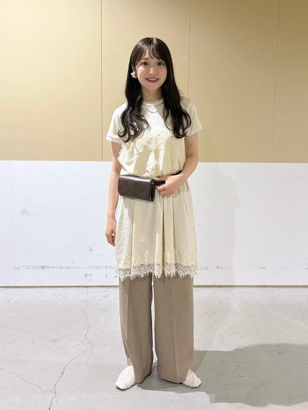 ベージュ系のスラックス、ブラウン系のボディバッグ/ウエストポーチ、ホワイト系のパンプスを着用したレディースの春コーディネートの2枚目の写真