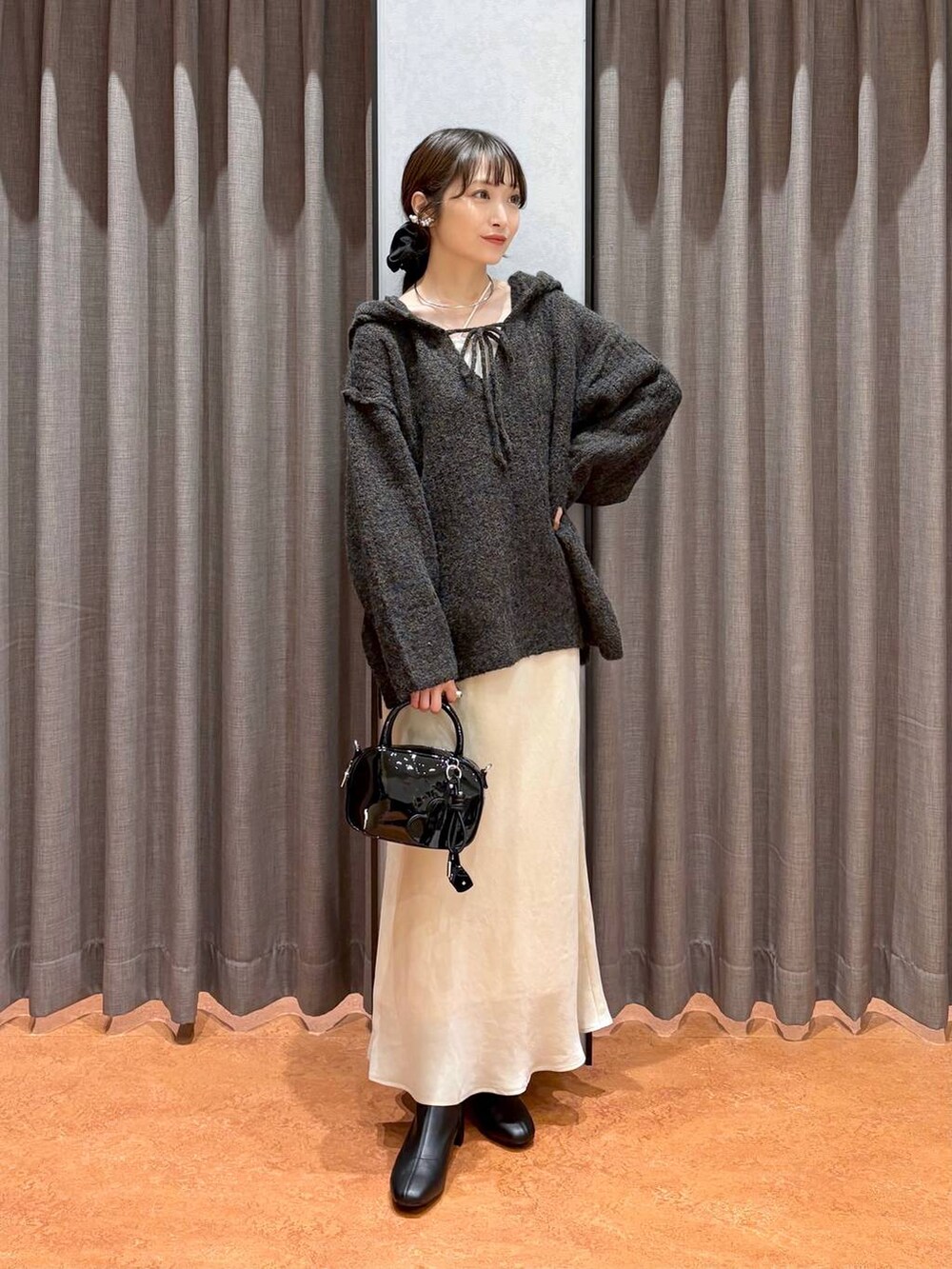 ベージュ系のキャミソール、ホワイト系のスカート、ブラック系のボストンバッグを着用したレディースの秋コーディネートの3枚目の写真