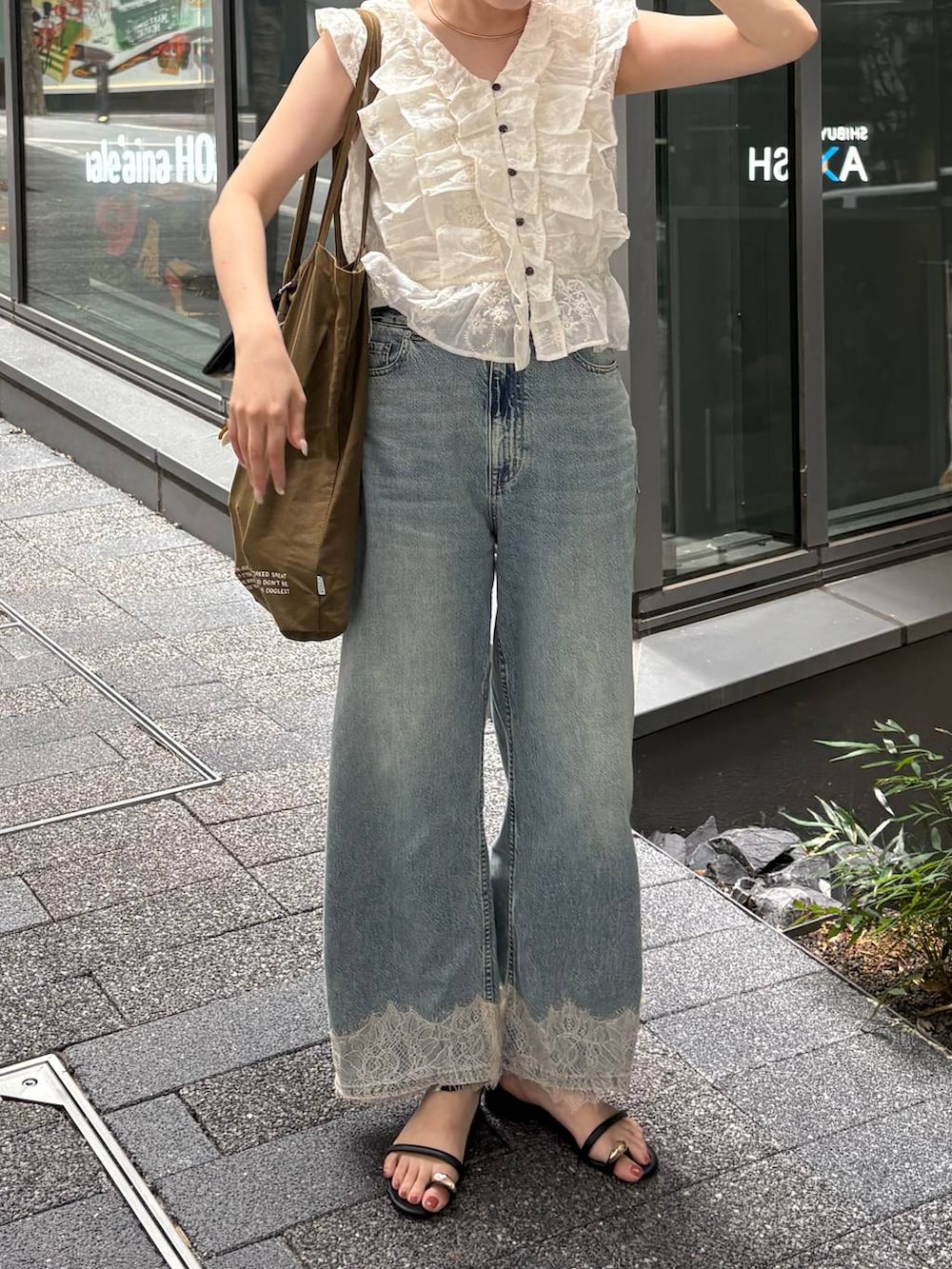 ブラック系のサンダル、ブルー系のデニムパンツ、ホワイト系のTシャツ/カットソーを着用したレディースの夏コーディネートの2枚目の写真